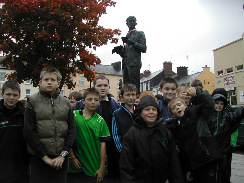 Group of school children stand in front of the Sam Maguire Statue in Dunmanway