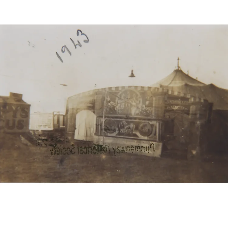 A sepia-toned archival photograph from 1943 showing an exterior view of the Duffy Circus grounds. The main attraction is a decorated wooden structure forming the grand entrance or ticket pavilion, which features large painted murals of mythological or classical figures on horseback. The canvas top of the main circus tent rises behind it under a pale sky. The year "1943" is handwritten in dark ink in the upper left corner.